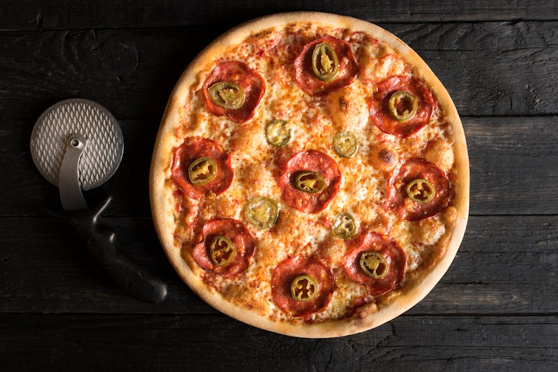 Signature coal-fired pizza with charred bubbles and rich tomato sauce